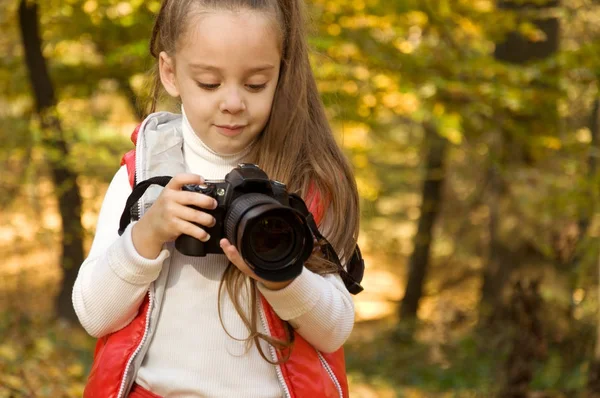 La niña sostiene una cámara y toma una foto. pasatiempo . — Foto de Stock