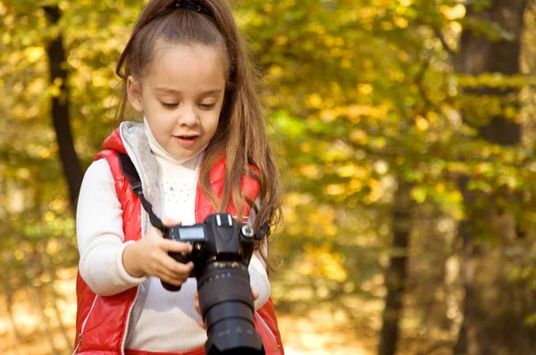 A menina está segurando uma câmera e tirando uma foto. hobby . — Fotografia de Stock