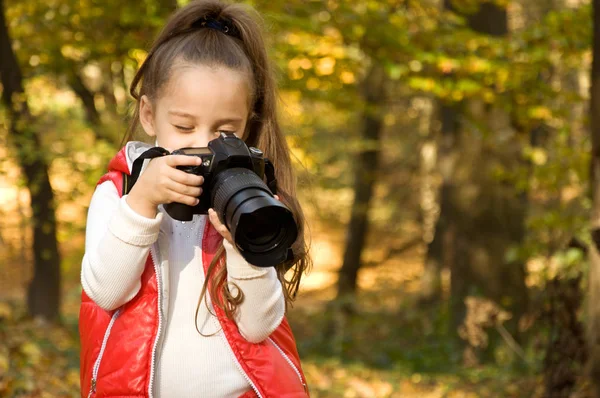 Malá holčička drží kameru a veselosti. koníček. — Stock fotografie