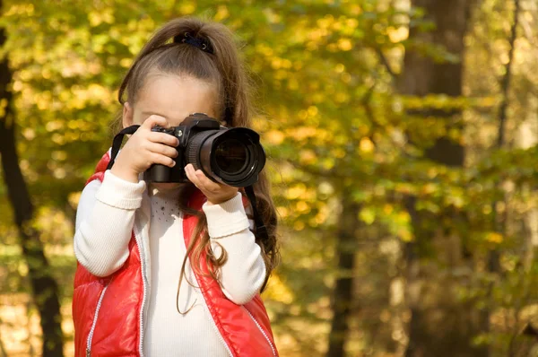 Malá holčička drží kameru a veselosti. koníček. — Stock fotografie