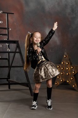 küçük kız elinde mikrofon ile. Genç yıldız.