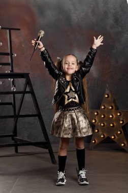 küçük kız elinde mikrofon ile. Genç yıldız.