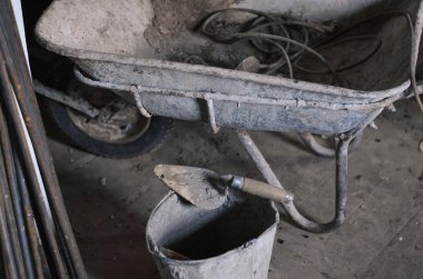 Kirli çimento el arabası sepeti bitmemiş çimento duvar arka plan ile inşaat sahasında.