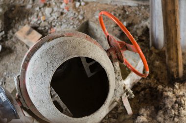 Yeni turuncu çimento karıştırıcı bir inşaat sahasında.