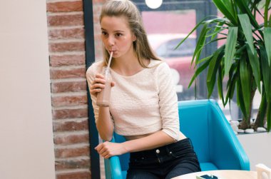 Detoks suyu ve Smoothies sağlıklı beslenmesi için. Güzel gülümseyen kadın oturuyor içinde kafe ile taze Detoks suyu içinde şişe ve içme, masada bardaklarda sebze güler yüzlü içer. Kilo Verme Diyet 