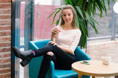 Detoks suyu ve Smoothies sağlıklı beslenmesi için. Güzel gülümseyen kadın oturuyor içinde kafe ile taze Detoks suyu içinde şişe ve içme, masada bardaklarda sebze güler yüzlü içer. Kilo Verme Diyet 