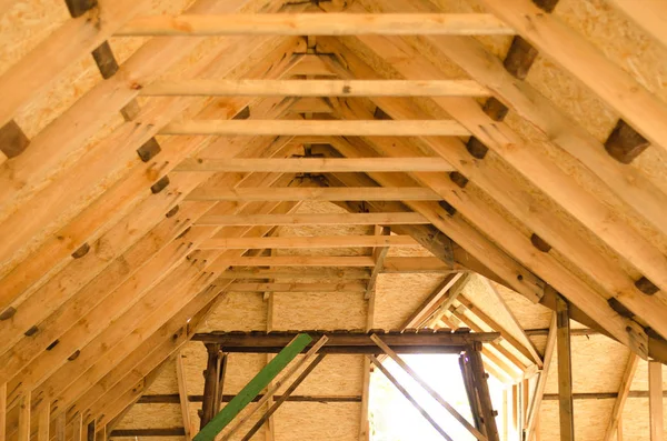 Raising roof truss to second story of new residential construction. Interior view of a wooden roof structure. roof preparation of OSB.