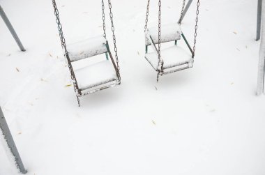 karla kaplı çocuksuz bir kar fırtınası içinde Çocuk salıncaklar