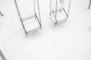 karla kaplı çocuksuz bir kar fırtınası içinde Çocuk salıncaklar