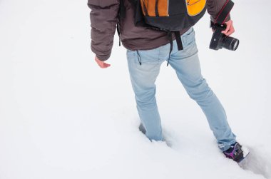 Tanınmayan fotoğrafçı elinde fotoğraf makinesi ile derin snowdrifts gider. fotoğrafçı ile turuncu sırt çantası