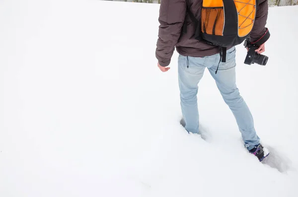 无法识别的摄影师用相机在他的手穿过深的雪堆。摄影师用橙色背包 — 图库照片