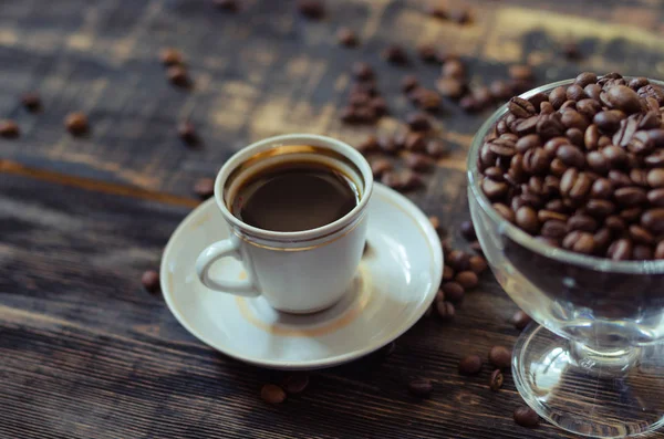 Cangkir kopi putih dan biji kopi dengan latar belakang kayu tua . — Stok Foto