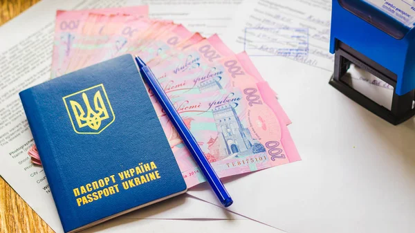 Belge arka plan üzerinde hryvnias ile uluslararası Ukrayna pasaportu. Ukraynalı para, belgeler, damga ve pasaport.