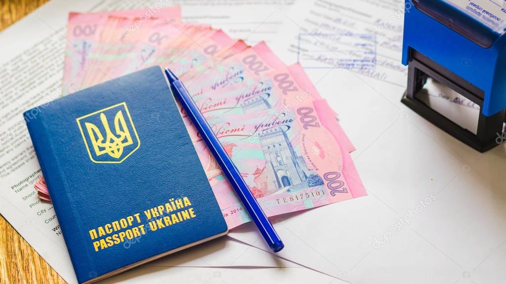 International Ukrainian passport with hryvnias on document background. Ukrainian money, documents, stamp and passport.