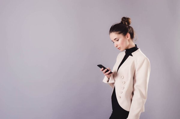 Portrait of a young attractive girl use smartphone isolated on a neutral gray background.