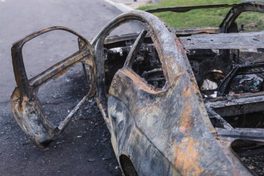 Şehirdeki yolda park etmiş hızlı bir araba yanmış. Araba artığı.