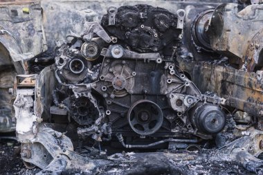 Şehirdeki yolda park etmiş hızlı bir araba yanmış. Araba artığı.