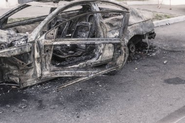 Şehirdeki yolda park etmiş hızlı bir araba yanmış. Araba artığı.