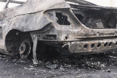 Şehirdeki yolda park etmiş hızlı bir araba yanmış. Araba artığı.