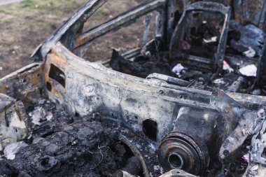 Şehirdeki yolda park etmiş hızlı bir araba yanmış. Araba artığı.