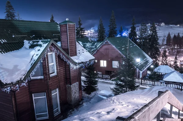 Fila de casas de madeira em uma rua coberta de neve no inverno à noite — Fotografia de Stock