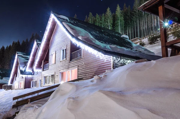 Fila de casas de madera en una calle cubierta de nieve en invierno por la noche Fotos De Stock Sin Royalties Gratis