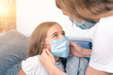 Anne, tıbbi maske takan kızına iyi bak. hastalıktan kurtulma