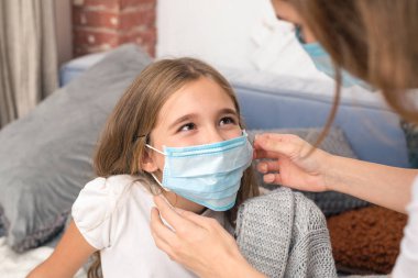 Anne, tıbbi maske takan kızına iyi bak. hastalıktan kurtulma