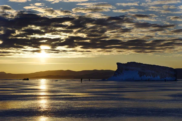 Kışın gün doğumu Baykal. Güneş bulutları delip geçer ve buzun yüzeyini yansıtır.