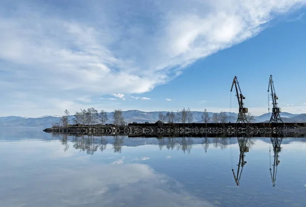 Mavi gökyüzüne karşı suyun yanında iki vinç