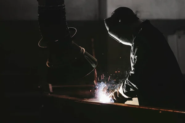 Worker at the factory in the helmet is of iron in the welding pr