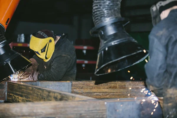 Worker at the factory in the helmet is of iron in the welding pr