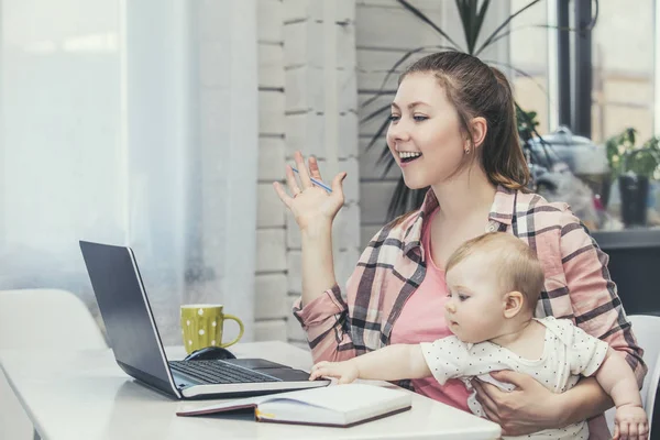 Family mother works with a laptop via the Internet and the baby