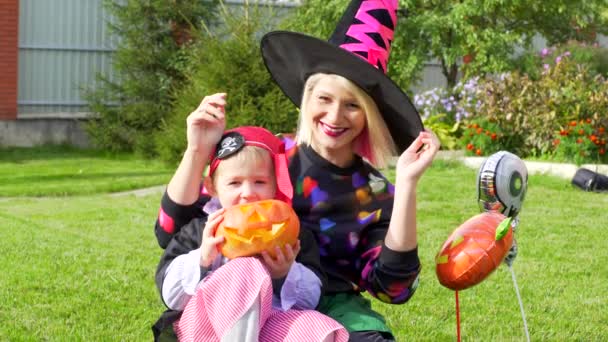 Мать и сын в костюмах на Хэллоуин веселятся на вечеринке в честь Хэллоуина с Джеком Латерном-Тыквой — стоковое видео