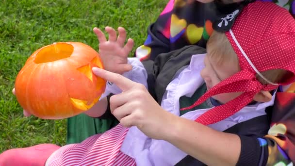 Мати і син в костюмах Хеллоуїна розважаються на вечірці на Хелловін з джеком топовим гарбузом — стокове відео