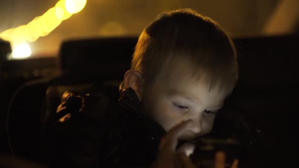 Little boy watching cartoon on phone sitting in baby car seat — ストック動画