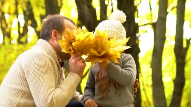 Отец и сын играют с осенним букетом желтых листьев — стоковое видео