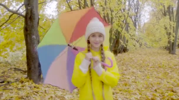 Jolie fille en imperméable jaune avec parapluie de couleur dans le parc d'automne 