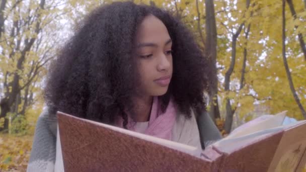 Gros plan de mignon noir adolescent fille avec dessin album en automne forêt — Video