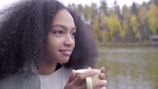 Ładna dziewczyna czarny Zawijanie siebie w wełniany pled i picie gorącej herbaty — Wideo stockowe