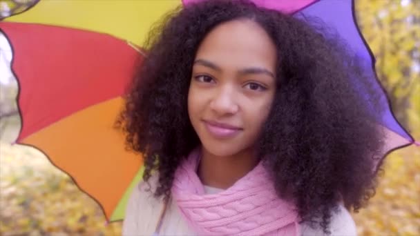 Cute black girl with colour umbrella in autumn park — Stock Video