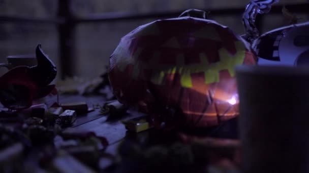 Mesa decorada con el símbolo de Halloween - Jack olantern, esqueleto, sombrero de bruja, caramelos y luces — Vídeo de stock