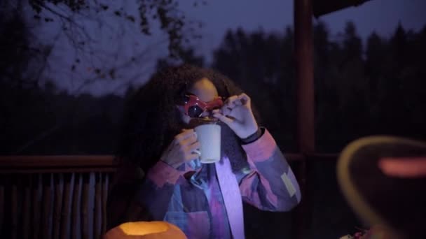 Милая черная девушка в маске дьявола пугает своего друга в ночь Хэллоуина — стоковое видео