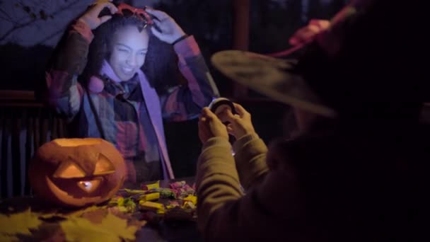Söt svart tjej i djävulen mask skrämmande hennes vän på Halloween — Stockvideo