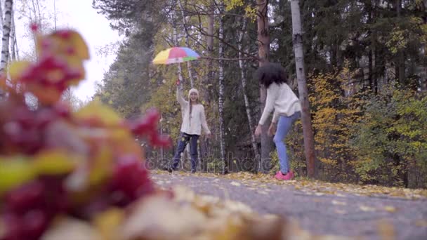 Linda adolescente niñas jugando en el bosque de otoño con sombrillas — Vídeos de Stock