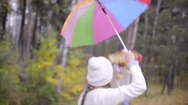 Adolescents heureux faisant pluie de feuilles avec parapluie 