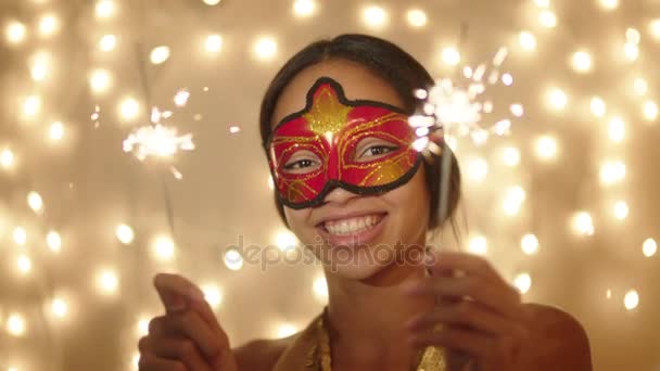 Hermosa joven con máscara de carnaval con luces de bengala en sus manos en la noche de Navidad — Vídeo de stock