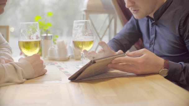 Dos hombres trabajando en la tableta y bebiendo cerveza en un ambiente relajado — Vídeos de Stock