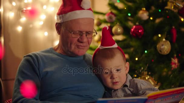 Grandpa reading book to his grandson on christmas eve — Stock Video