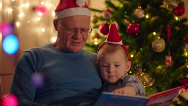 Abuelo leyendo libro a su nieto en la víspera de Navidad — Vídeos de Stock